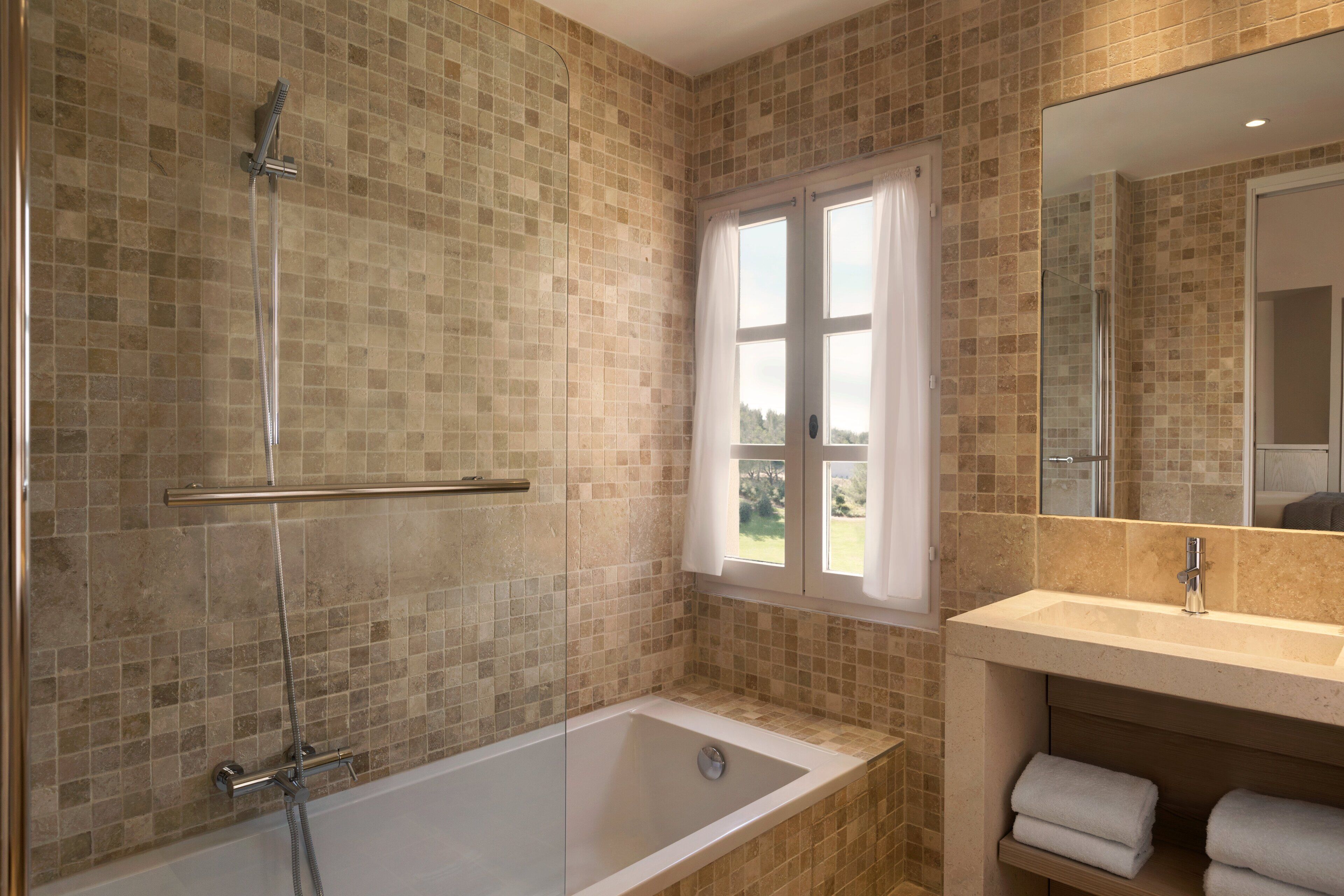 Un baño con ducha de vidrio, bañera y lavabo con espejo.
