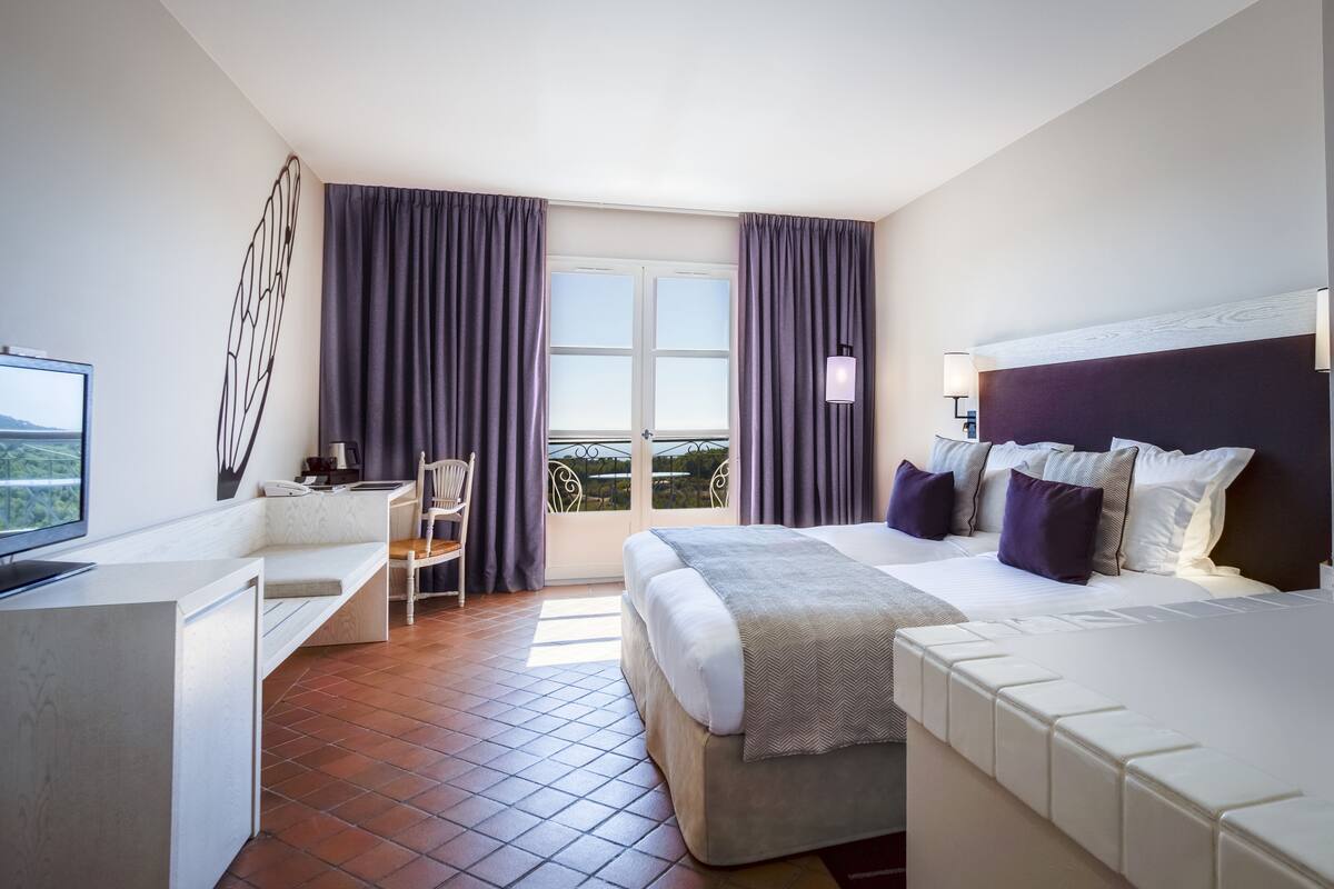 A hotel room with a bed, a desk, a chair, and a TV.
