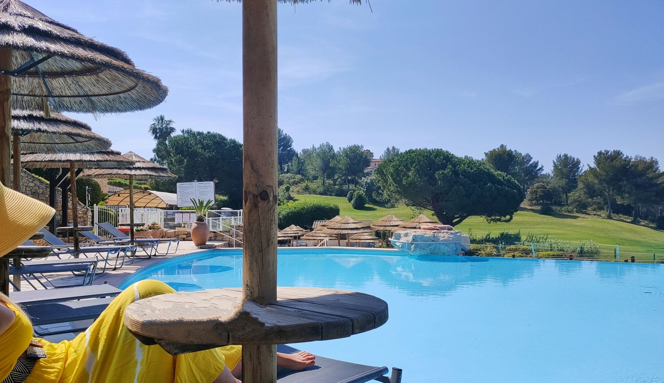 Area piscina con lettini e ombrelloni, circondata da un giardino curato e vista sulla campagna.