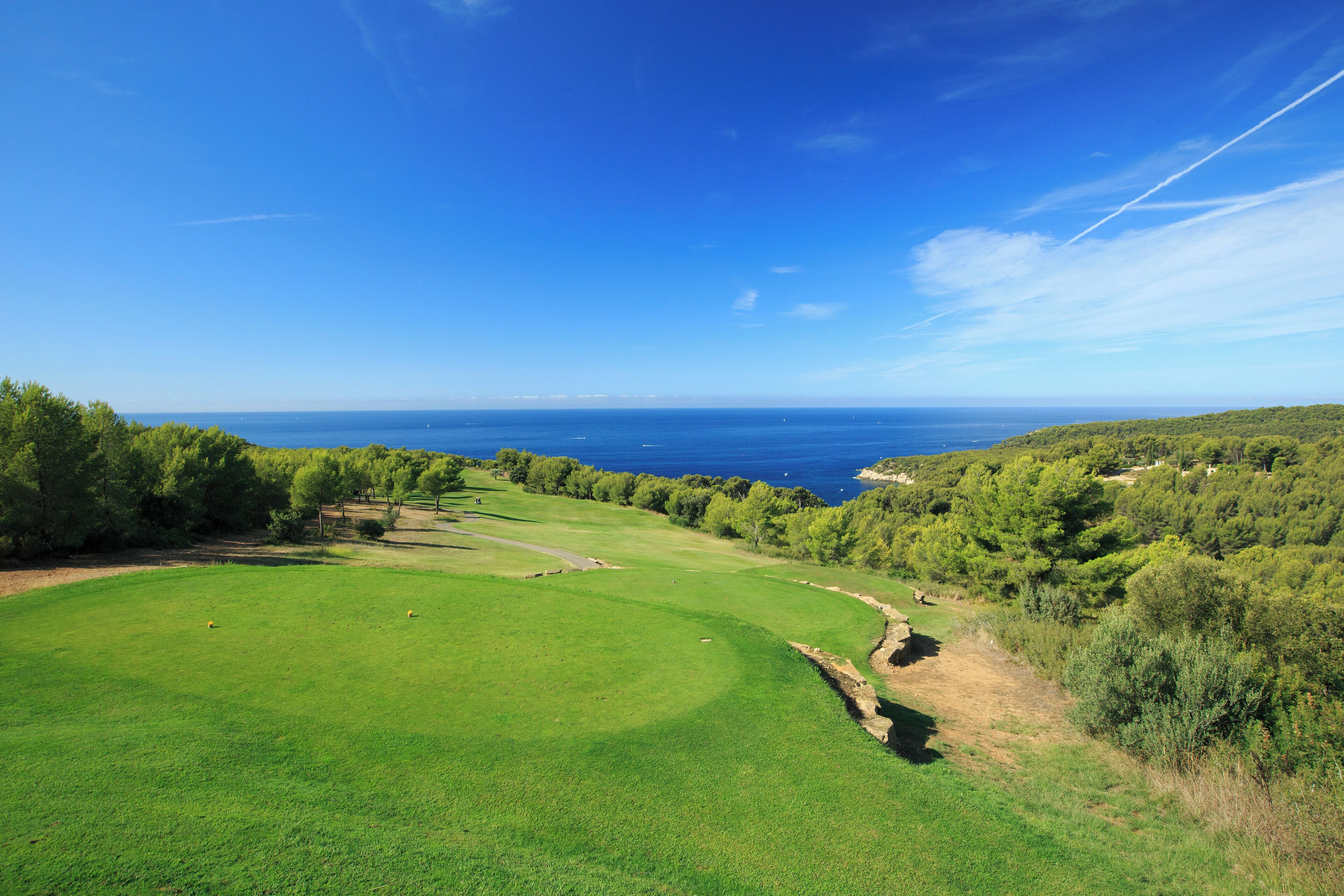 A golf course with a view of the sea and hills.