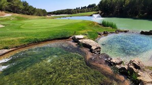 A golf course with a pond, clear water, and surrounding greenery. - Le Frégate Provence (Saint-Cyr-sur-Mer)