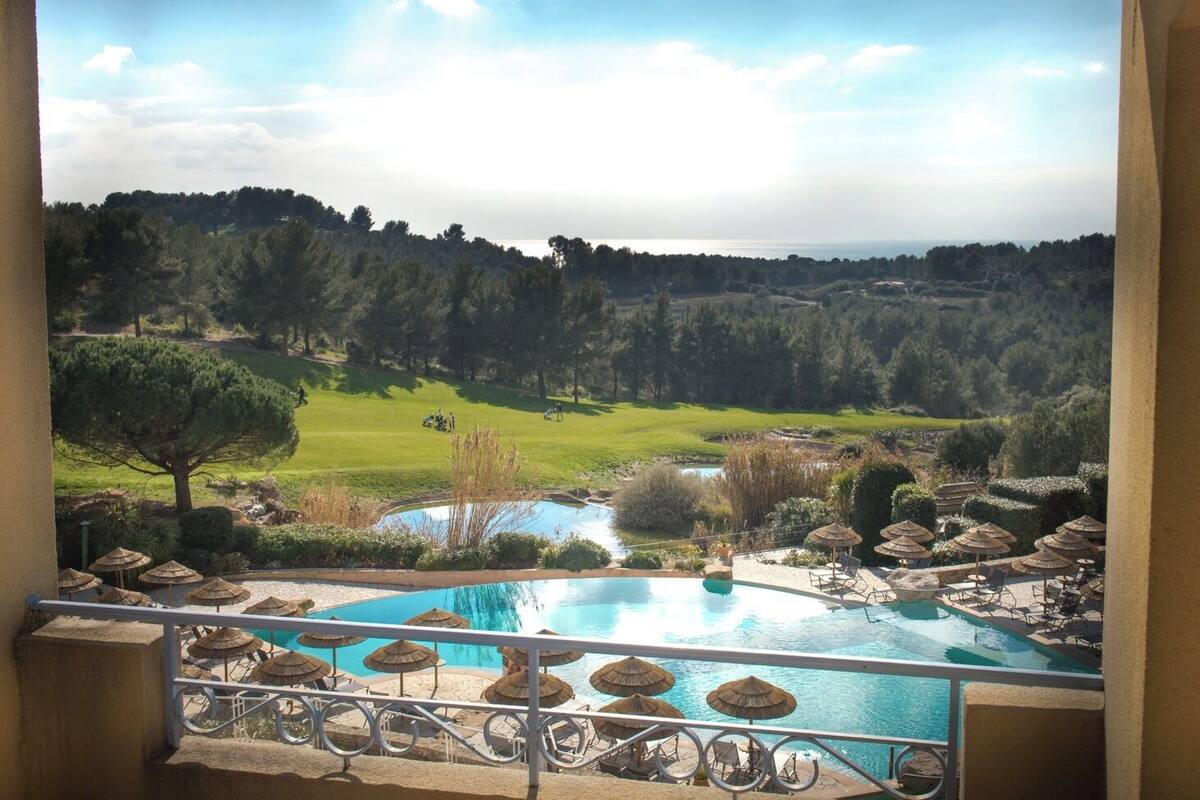 A pool with a view of a golf course and a forested area.