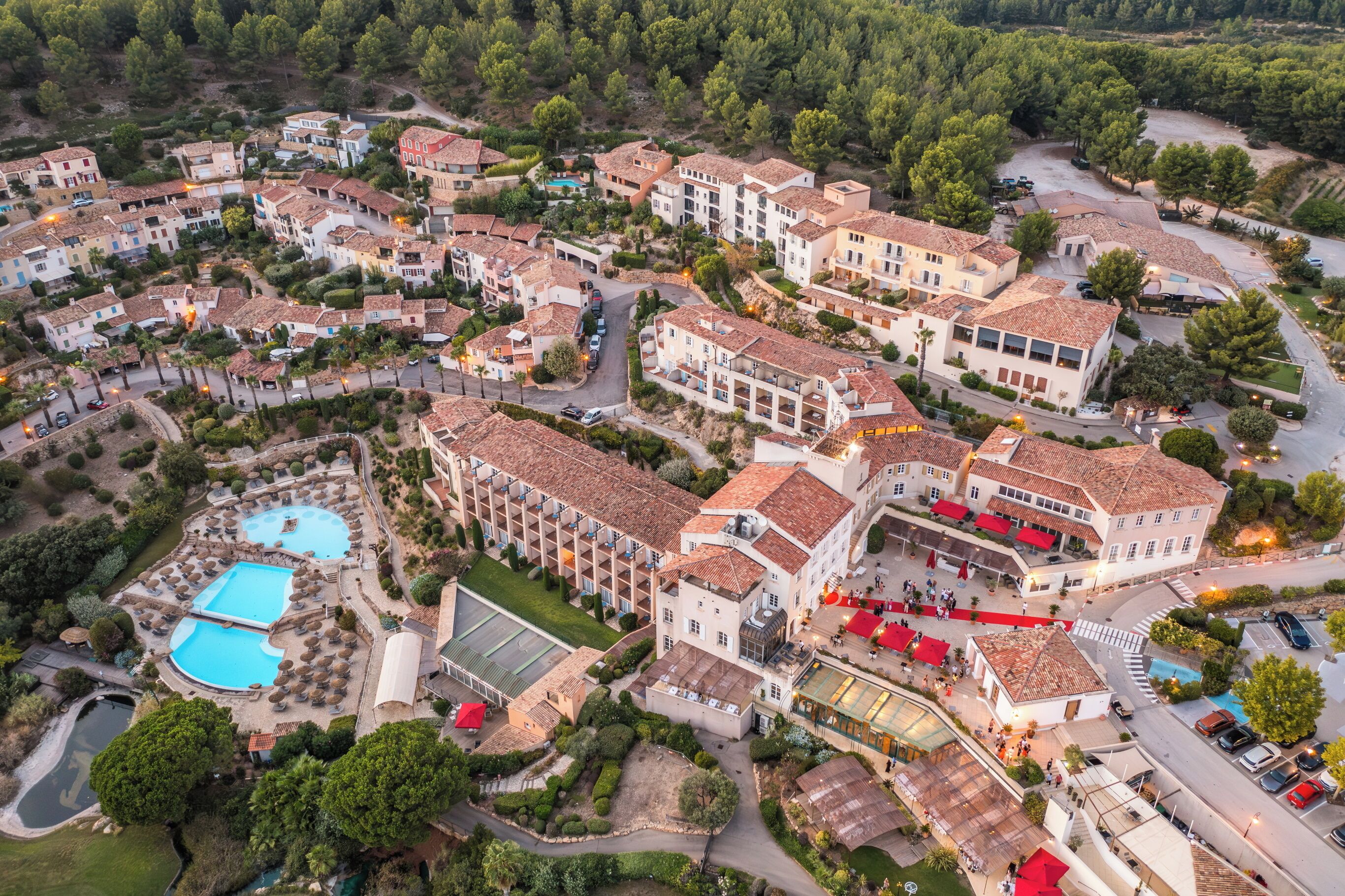 Vue aérienne d’un complexe hôtelier comprenant plusieurs bâtiments, des piscines et des espaces paysagers.