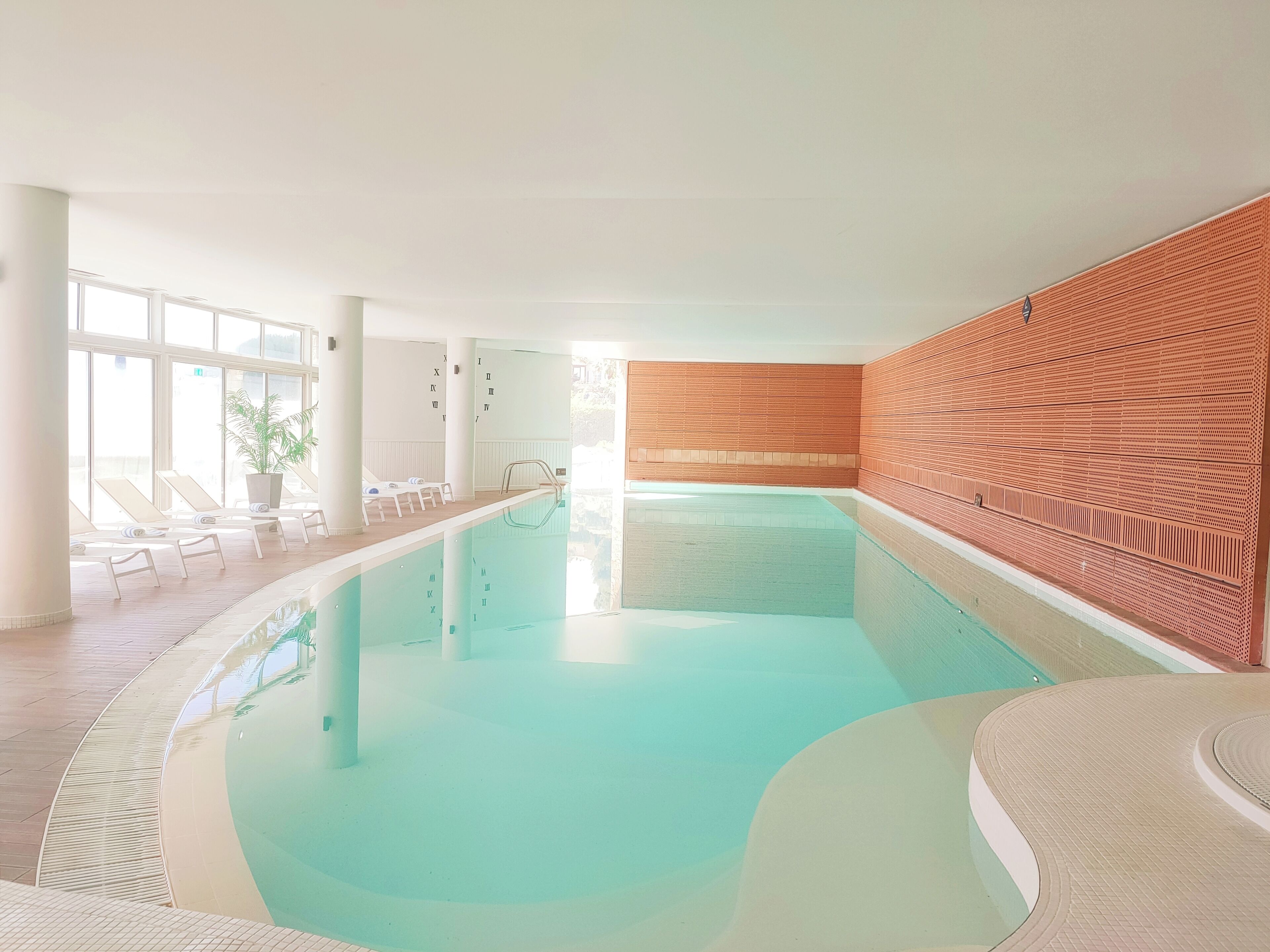 A swimming pool with lounge chairs and a wooden wall.