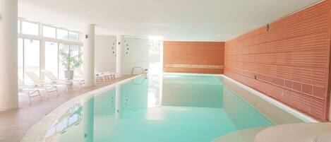 A swimming pool with lounge chairs and a wooden wall.