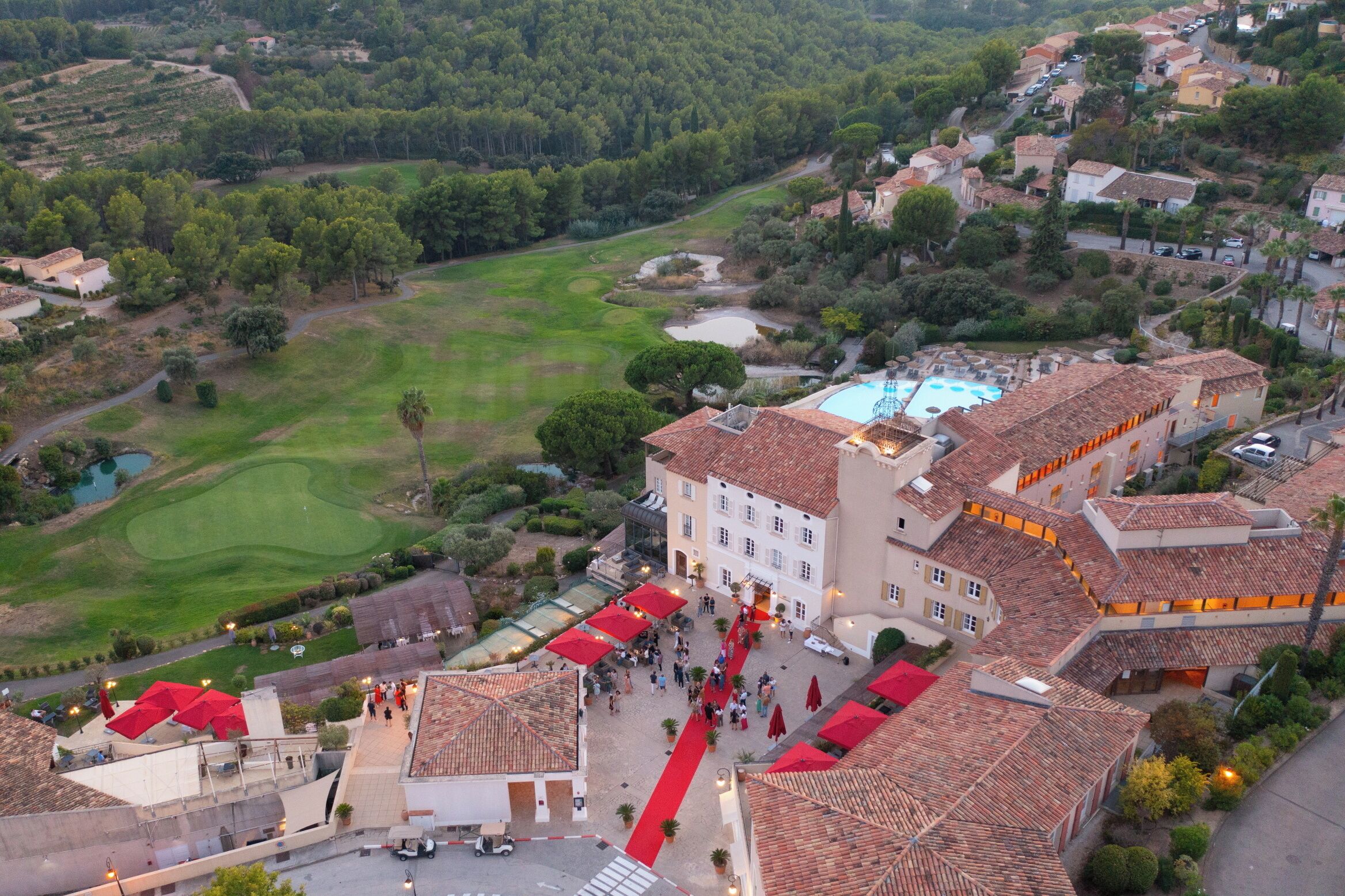 Vue aérienne d’un hôtel doté d’une cour intérieure, d’une piscine et, au loin, d’un terrain de golf.