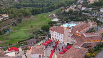 Vue aérienne d’un hôtel doté d’une cour intérieure, d’une piscine et, au loin, d’un terrain de golf.