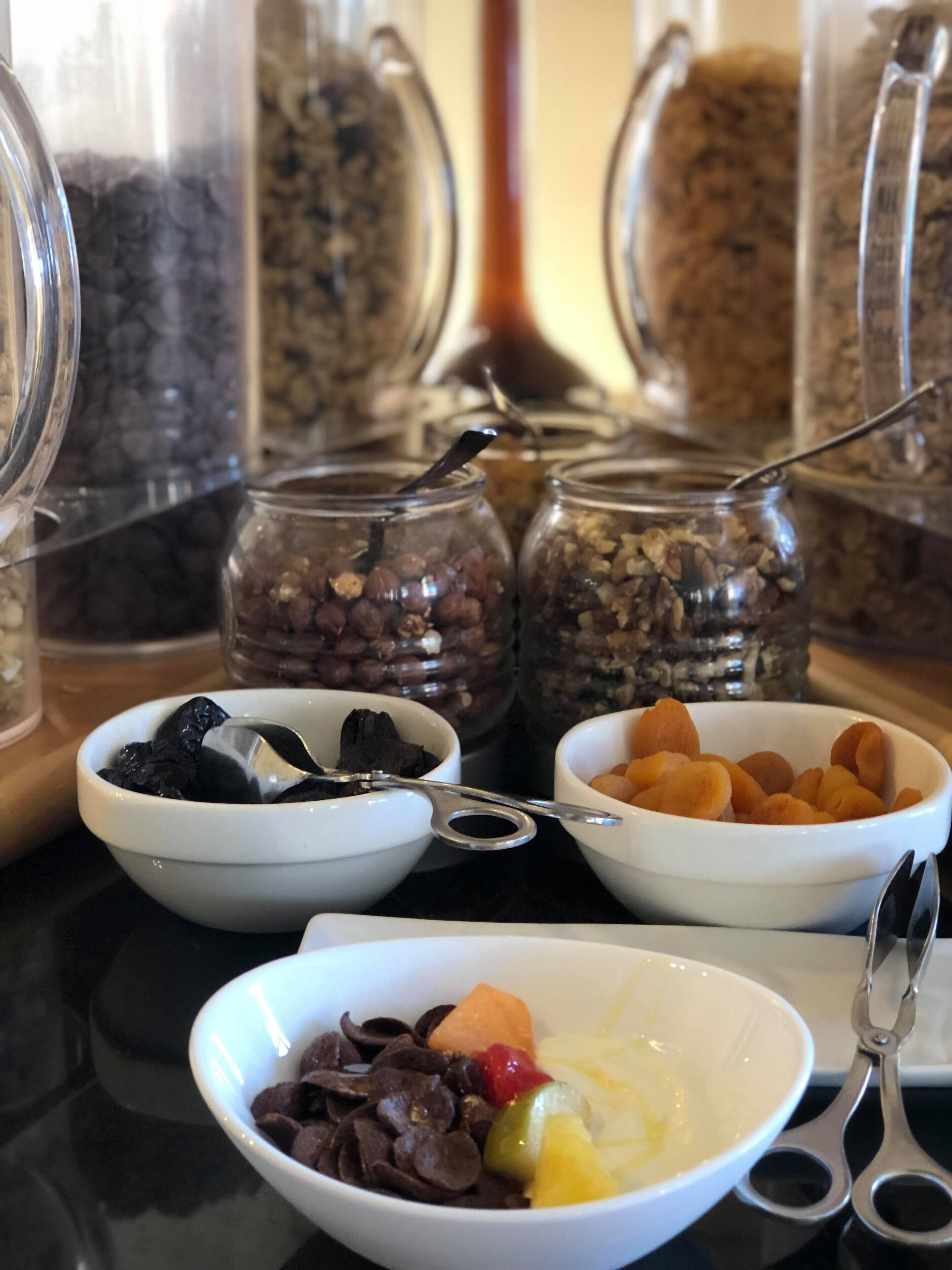 A table with bowls of assorted nuts and dried fruits, and jars of grains.