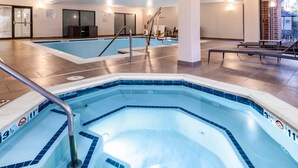 Une grande piscine intérieure dotée d’un jacuzzi, d’une eau cristalline et d’une zone de pont en carrelage.