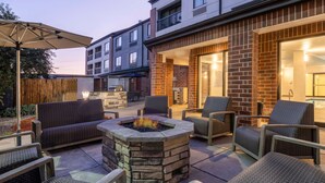 Un espace extérieur aménagé en terrasse, avec un foyer en pierre, des meubles en osier et un coin salon abrité.