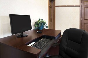 Un escritorio de madera con un monitor de computadora, teclado y una planta en maceta.