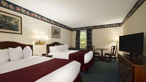 Ein Hotelzimmer mit zwei Betten, einem Fernseher, einem Schreibtisch und einem Sessel.