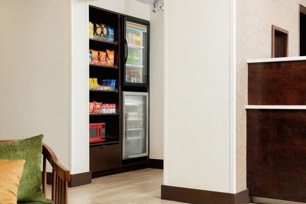 Una kitchenette equipada con refrigerador y estantes llenos de refrigerios y bebidas.