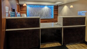 Ett välkomstområde med en väggpanel i trä, ett stort fönster med ett trädmönster och en receptionsdisk.