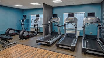 Een sportschool met loopbanden, elliptische trainers en een roeimachine.
