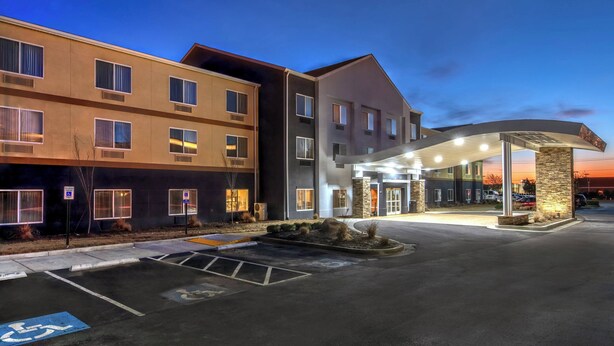 Ett hotell med flera våningar och modern design, med en ingång som är skyddad från väder och vind samt en parkeringsplats med tillgänglighet för personer med funktionsnedsättning.