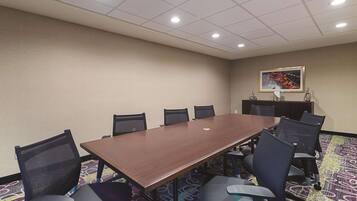 A conference room with a long table, chairs, a patterned carpet, and a ceiling with recessed lighting.