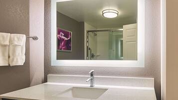 Un baño con un espejo grande, un lavabo y un perchero para toallas.