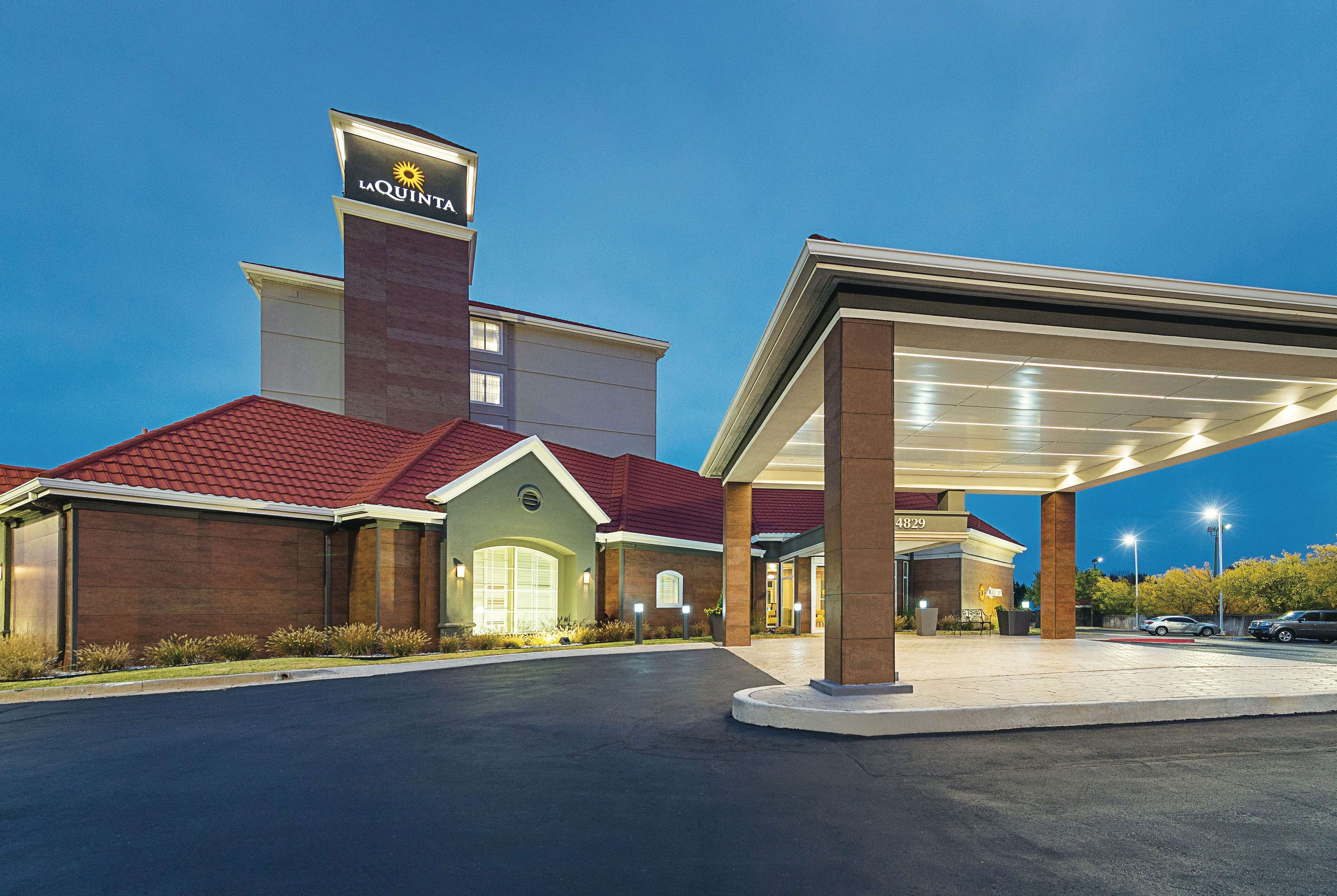 A hotel with a red roof, a prominent sign, and a covered parking area.