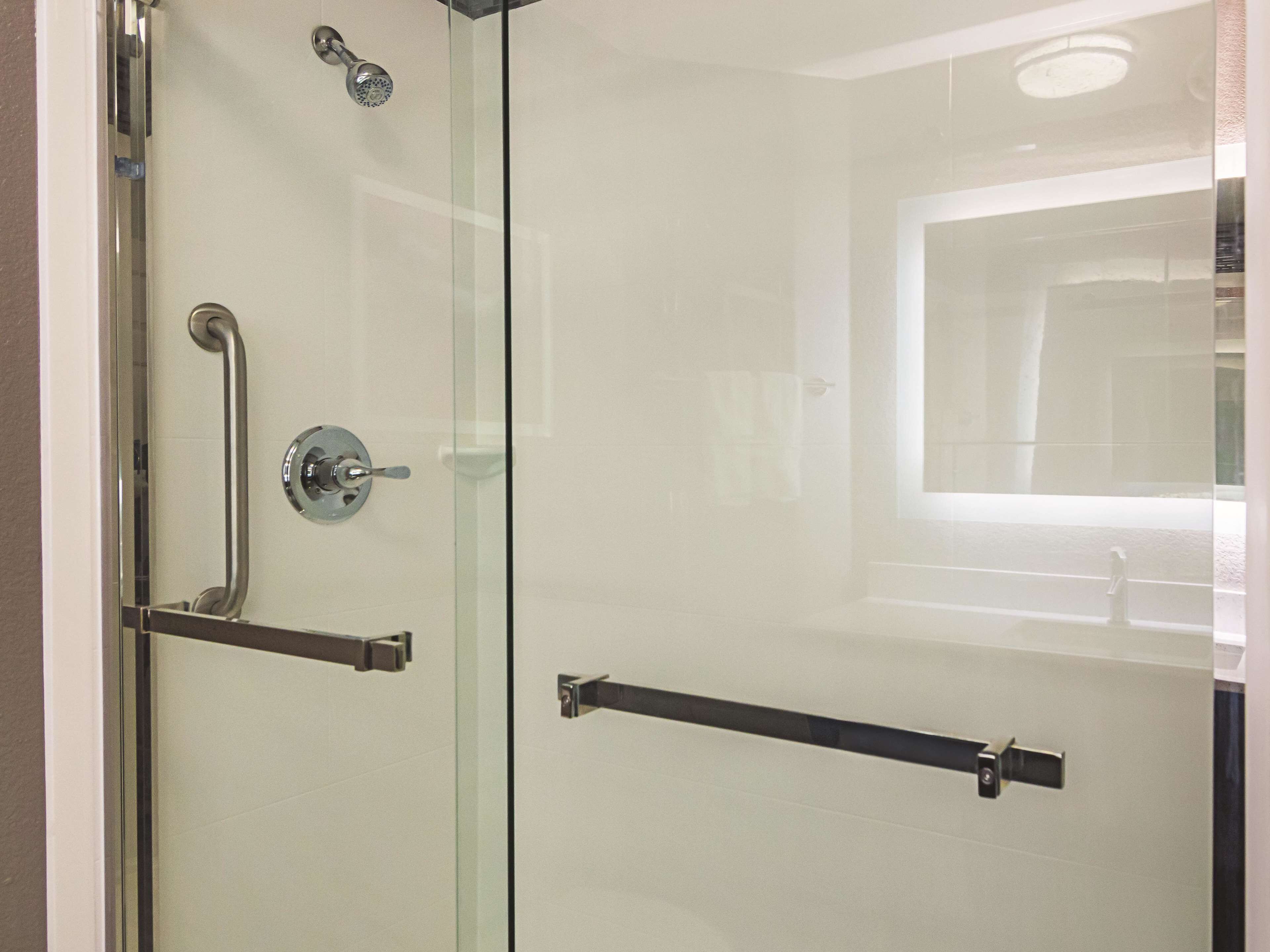 A modern bathroom with a glass shower enclosure, a handheld showerhead, and a towel rack.