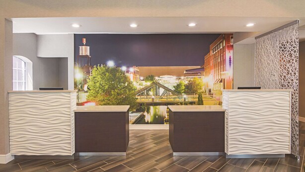 A modern reception area with a view of a cityscape at night, featuring a bridge and illuminated buildings. - La Quinta Inn & Suites by Wyndham Oklahoma City - NW Expwy (Oklahoma City)