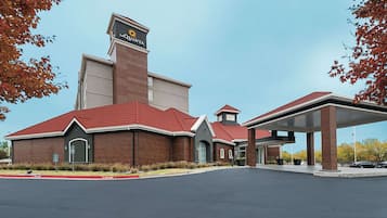 A hotel with a red roof, a prominent sign, and a covered parking area.