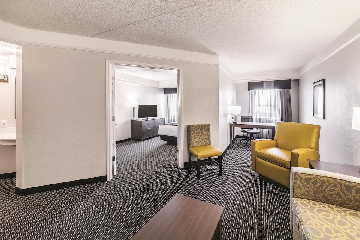 Une chambre d’hôtel équipée d’un lit, d’un bureau, d’une chaise, d’un canapé et d’une télévision.