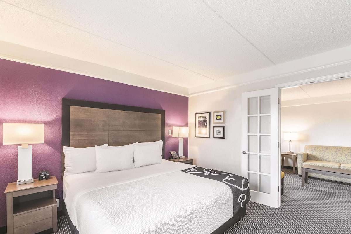 Une chambre d’hôtel avec un grand lit, une table de chevet avec une lampe, une petite table avec une lampe et un canapé.