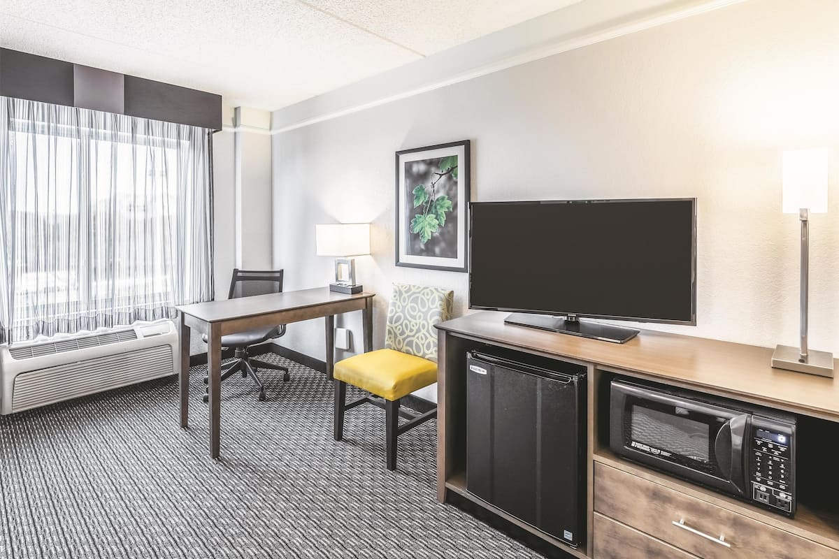 Une chambre d’hôtel équipée d’une table à manger, de chaises, d’un téléviseur à écran plat, d’un four à micro-ondes et d’un petit réfrigérateur.