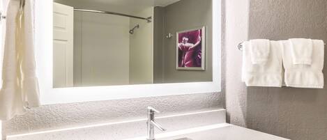 Une salle de bain avec un grand miroir, un lavabo et un porte-serviettes avec deux serviettes.