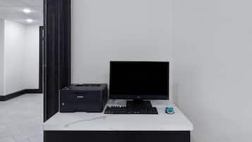 A desk with a computer, keyboard, and printer in a modern office setting.