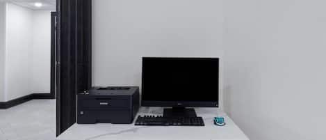 Un escritorio con computadora, teclado e impresora en una oficina moderna.