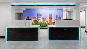 Een receptiegedeelte met marmeren balies, een stadsgezichtsmural en een klok aan de muur.
