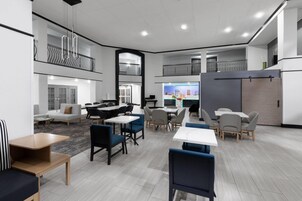 A modern, multi-level dining area with tables and chairs, a sofa, and a balcony.