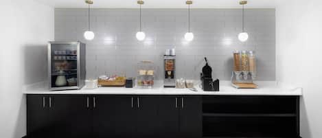 A modern kitchen with a white countertop, black cabinets, and a marble-patterned floor.