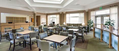 Un hall de hotel espacioso con varias zonas de estar, una recepción y amplios ventanales que dejan entrar luz natural.