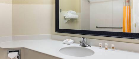 Un baño con un lavamanos blanco, un espejo y un perchero para toallas.