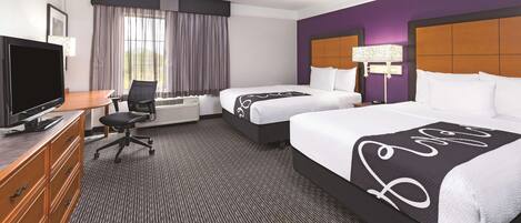 A hotel room with two beds, a desk with a TV, a chair, and a dresser.