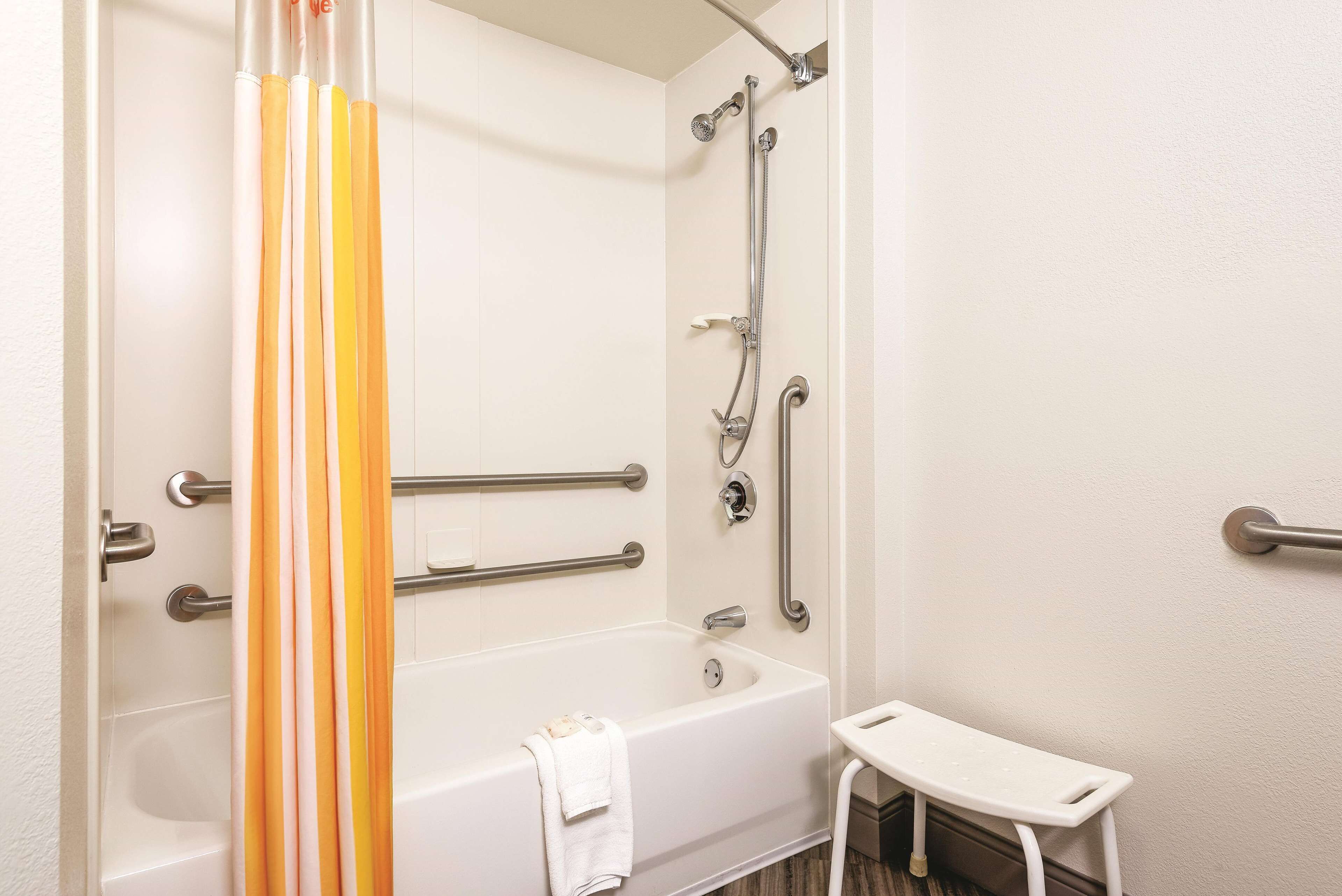 Bagno con vasca, doccia e maniglie di sostegno.