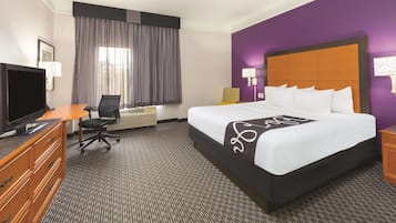 Une chambre d’hôtel avec un grand lit, un bureau avec un ordinateur, une télévision et une chaise.