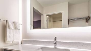 A bathroom with a white countertop sink, a mirror, and a towel rack.