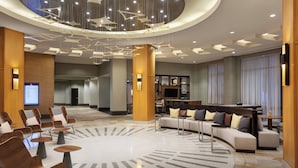 Un'ampia hall con area salotto centrale, un design moderno del soffitto e una reception.