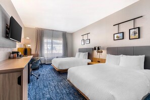 A hotel room with two beds, a desk, a TV, and a window with curtains. - Sleep Inn (Cedar Hill)