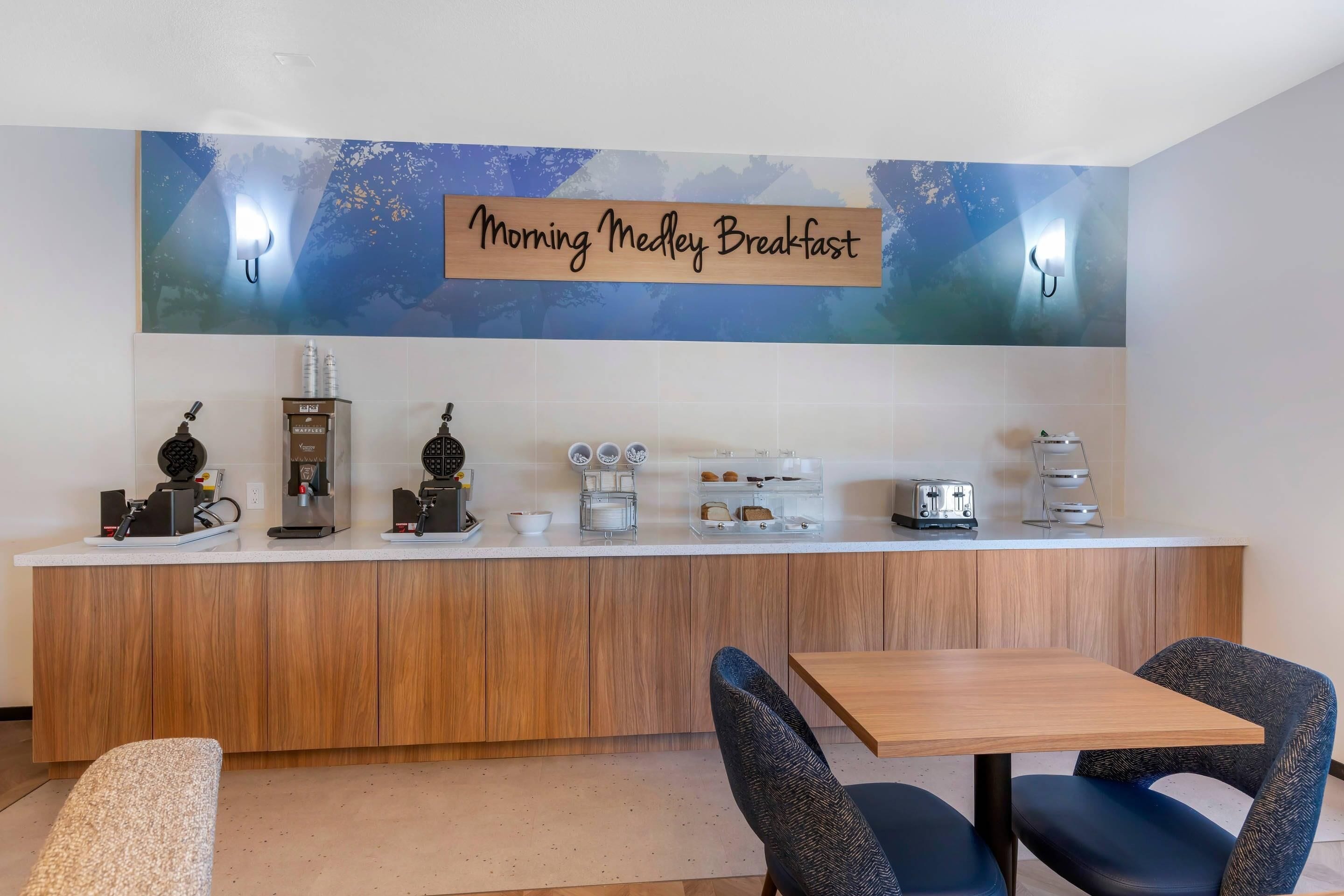 A breakfast bar with a sign reading 'Morning Medley Breakfast', equipped with a coffee machine, waffle maker, and toaster.