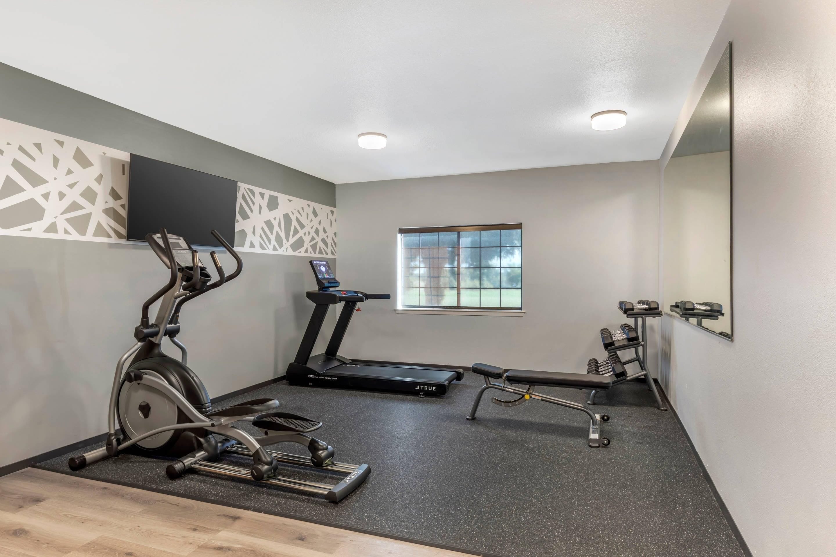 A gym with exercise equipment, a treadmill, and a window with a view.