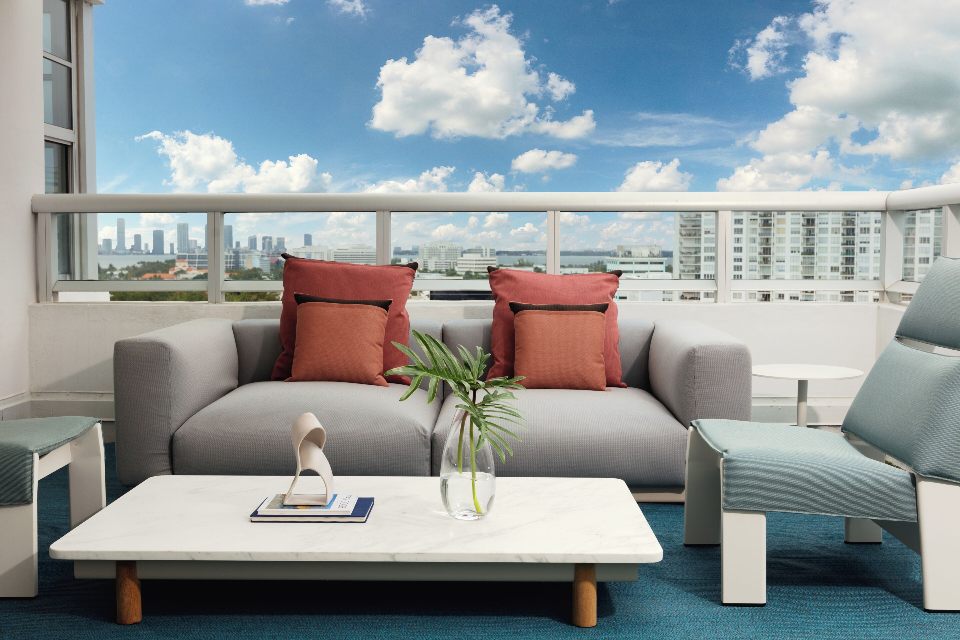 Una sala de estar moderna con un sofá, sillones, una mesita de centro y vistas a un horizonte urbano.