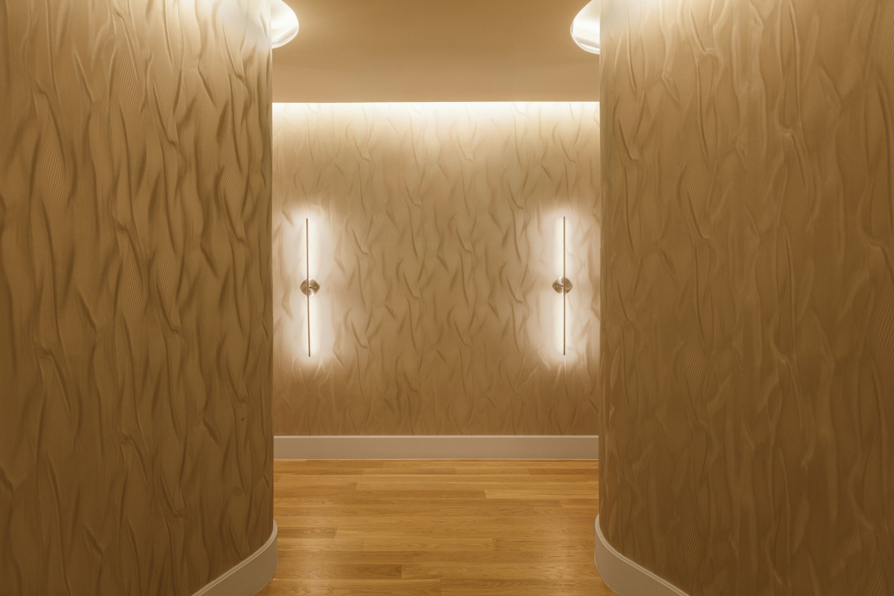 Un pasillo con piso de madera y paredes con textura.
