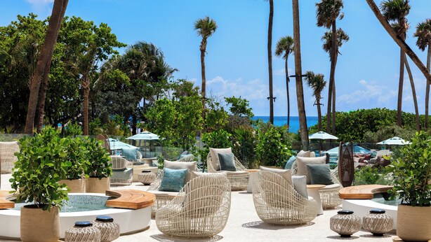 A poolside area with wicker furniture, potted plants, and umbrellas. - Andaz Miami Beach Resort & Spa (Miami Beach)
