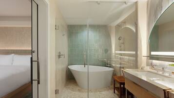 A modern bathroom with a glass-enclosed shower, a freestanding bathtub, and a vanity with a mirror.