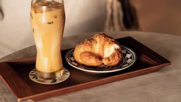 Una bandeja con un vaso de café helado y un croissant sobre una mesa en un ambiente interior acogedor.